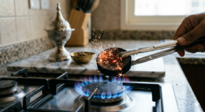 How to light charcoal for bukhoor - holding charcoal disc with metal tongs over a flame in Dubai